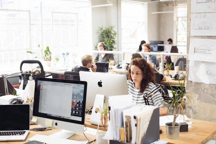 Woman working on an apple computer at the office with a serious face