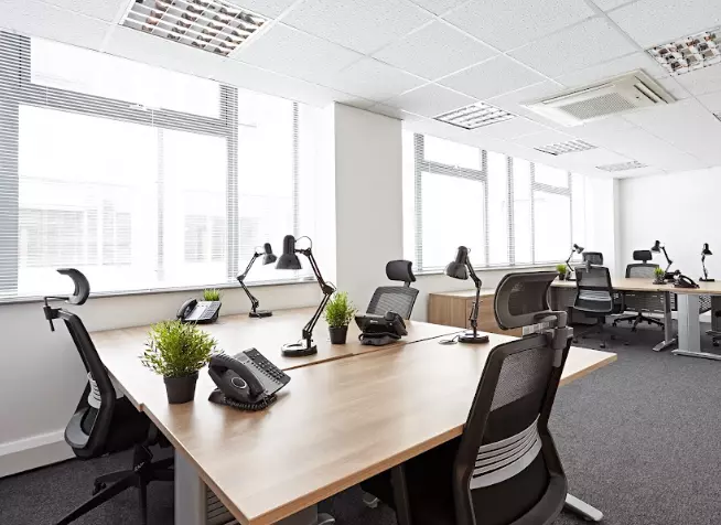 An office with black chairs and wooden desks.