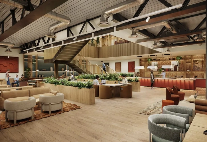 Coworking area at 60 London Wall showcasing a large industrial style room with beige couches, plant dividers a balcony and cafe