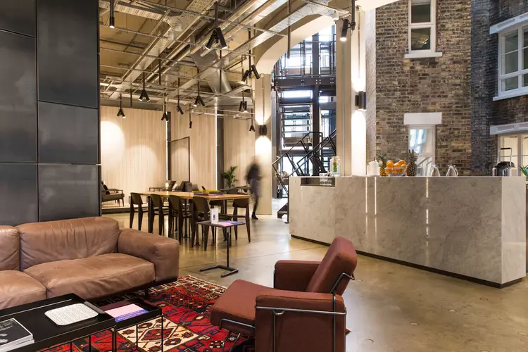 Breakout and reception space at FORA The Stanley Building featuring an industrial style of design with concrete flooring and exposed cellings 