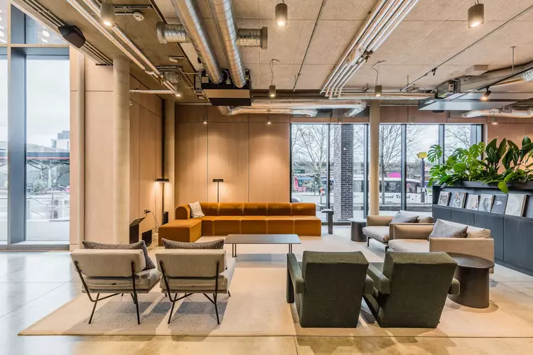 Breakout Space at FORA Tintagel House with a big orange couch and two green chairs and four grey seats
