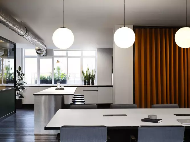 Office and Kitchen space at FORA Wardour Street in London with an orange curtain and plants in the background