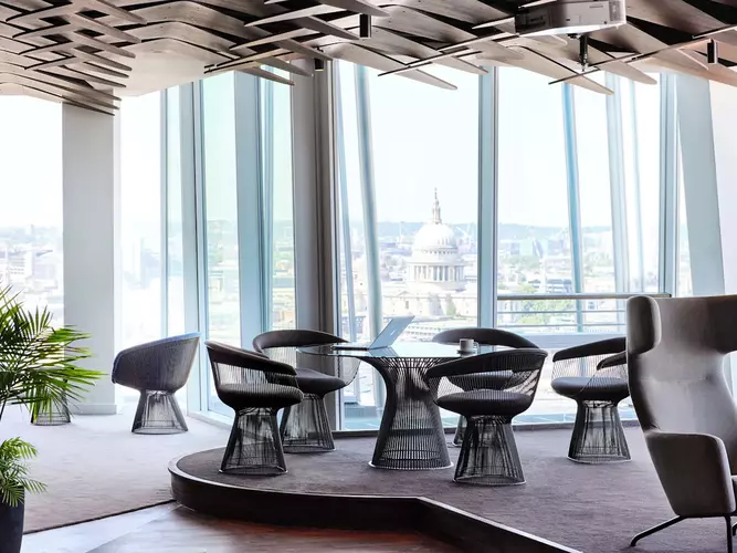 Coworking space at FORA 24/25 The Shard with grey chairs around tables and long grey sofa
